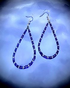 These beautiful 2 3/4" earrings are made with blue and purple and silver seed beads. These beads are a nice embellishment to the classic teardrop hoop earrings. These teardrop earrings are very comfortable because they are so lightweight.  Hoop earrings are classic, and these are teardrop hoops, with a pattern that makes a statement. You can't go wrong with these earrings! They are great all year round. These would be great on to wear on July fourth! They come in a box for easy gift giving too. They are a great birthday, Mother's Day, or Christmas gift! 1006 Dangle Teardrop Earrings With Tiny Beads As Gift, Gift Teardrop Dangle Earrings With Tiny Beads, Blue Teardrop Hoop Earrings With Dangling Beads, Silver Teardrop Beaded Earrings, Blue Teardrop Jewelry With Silver Beads, Blue Hoop Earrings With Dangling Beads Gift, Handmade Blue Teardrop Hoop Earrings, Blue Beaded Teardrop Earrings For Gift, Blue Dangle Hoop Earrings With Tiny Beads