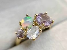 three different colored stones on top of a gold plated ring with white and pink opals