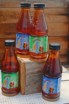 four bottles of apple cider sitting on top of a piece of wood