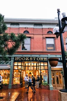 people are walking in front of bookstores on a rainy day with the lights on