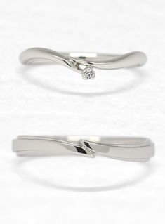 two wedding rings, one with a diamond on top and the other with a curved band