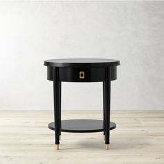 a black round table with gold accents on the bottom and one drawer at the top