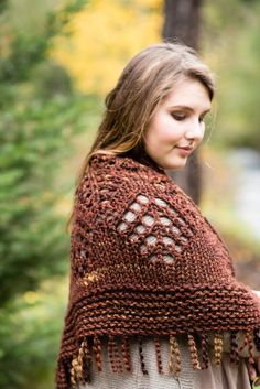 a woman wearing a crocheted shawl in the woods