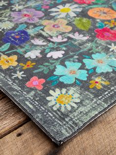 an area rug with flowers on it sitting on a wooden floor next to a piece of wood