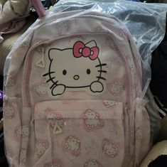 a hello kitty backpack sitting on top of a pile of stuffed animals