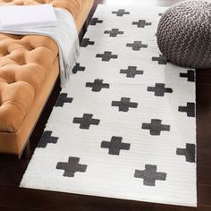 a white rug with black crosses on it in a living room next to a couch