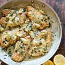 chicken with lemon sauce in a pan on a wooden table