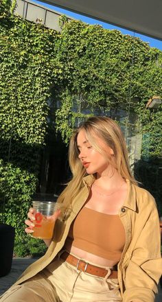 a woman sitting on the ground holding a drink