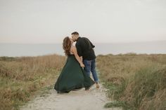 a man and woman walking down a path in the sand with their arms around each other