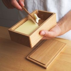 a person is dipping cheese into a wooden container