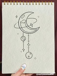 someone is holding up a drawing with the moon and stars hanging from it's side