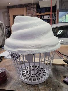 a white birdcage sitting on top of a wooden table next to a car