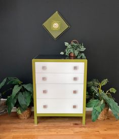 a green and white dresser next to some plants