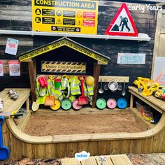 an outdoor construction area made out of wood and sand with toys on the ground next to it