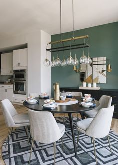 the dining room table is set with white chairs and plates on it, along with an area rug