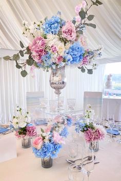 there are many flowers in the vases on this dining room table set for an event