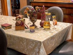 a dining room table with two vases filled with flowers and other items on it