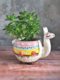 a ceramic planter with a small potted plant in the shape of a llama