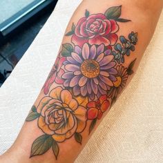 a woman's arm with flowers and leaves on it