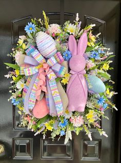 an easter wreath with bunny ears, flowers and eggs on the front door for decoration