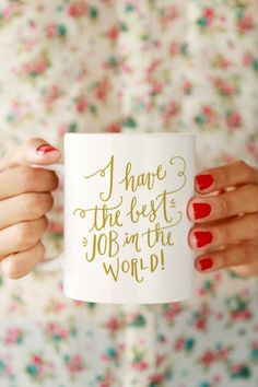 a woman holding a coffee mug that says i have the best job in the world