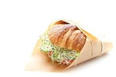 a sandwich wrapped in brown paper on top of a white background with the words perfect picnic croissant