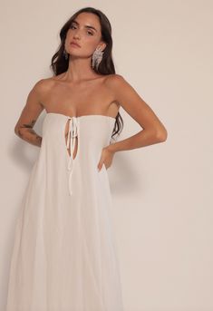 a woman in a white dress with her hands on her hips