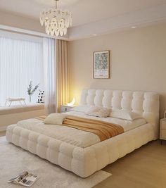 a large white bed sitting in a bedroom next to a window filled with light colored curtains