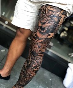 a man's leg with a tiger tattoo on it and flowers around the legs