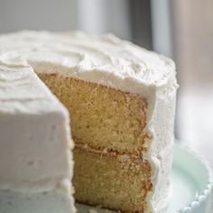 a cake with white frosting is on a plate and has one slice cut out