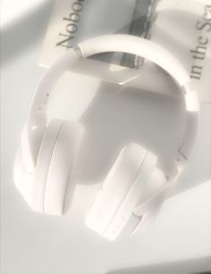 a pair of white headphones sitting on top of a table next to a book