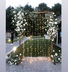 an outdoor wedding ceremony with white flowers and fairy lights on the grass, surrounded by greenery