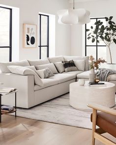 a living room filled with lots of furniture next to large windows and a white rug on the floor