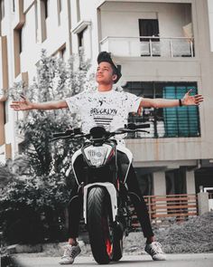 a man sitting on the back of a motorcycle with his arms outstretched in front of him