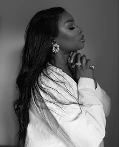 a black and white photo of a woman with her hands on her face, looking off to the side