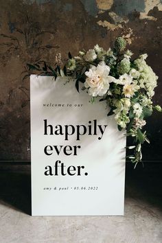 a sign that says happily ever after with flowers on it in front of a wall