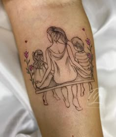 a woman with two children sitting on her lap and holding hands behind her back tattoo