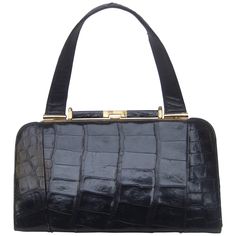 Sleek ebony vintage alligator leather handbag ca 1960s The stylish retro handbag is covered with glossy black alligator skin The handbag is designed with a sleek gilt metal clasp frame and hardware The interior is lined in ivory color vinyl designed with a zipper compartment and small pouch pocket compartment The vintage handbag is chic and timeless Measurements The handbag measures 12" inches in length across the top The length across the base of the handbag measures measures 12" 1/4 inches The handbag height from the clasp opening to the base = 7" inches The height from top of the handle to the base of the handbag measures 13" 3/4 inches The depth at the base widest section measures 2" 1/2 inches Cage Bag, Alligator Handbags, Crocodile Handbags, Black Alligator, Retro Handbags, Alligator Skin, Chloe Handbags, Patent Leather Handbags, Suede Handbags