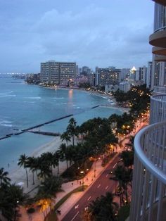 an ocean view from a high rise building overlooking the beach and city lights at dusk