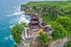 an aerial view of a cliff overlooking the ocean with some huts on it's roof