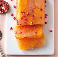 two pieces of fish on a plate with pomegranates next to it