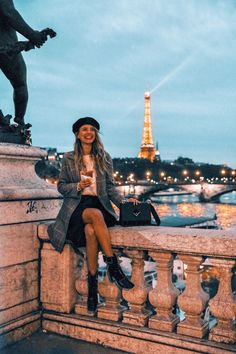 a woman sitting on top of a bridge next to the eiffel tower