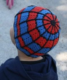 a young boy wearing a crocheted spiderman hat on top of his head