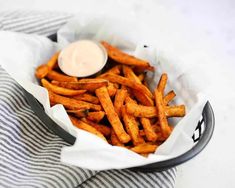 a basket filled with french fries covered in ketchup on top of a table