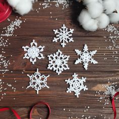 snowflakes and cotton on a wooden table with red ribbon, scissors and twine