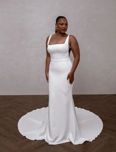 a woman in a white dress is standing on a wooden floor and posing for the camera