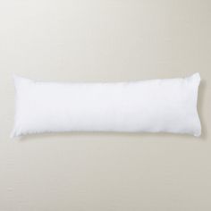 a white pillow sitting on top of a bed next to a beige wall and floor