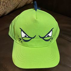 a green baseball cap with blue eyes on the front, and an angry face on the back