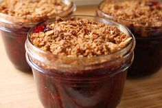 three jars filled with dessert sitting on top of a wooden table