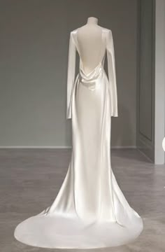 the back of a white wedding dress with long sleeves and a low neckline on display